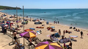 A crowded beach with umbrellas, beach chairs, and people enjoying the water. - Tresowes Green Cottage (Helston)