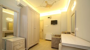A hotel room with a large wardrobe, a television, and a mirror. - Ataol Otel (Bozcaada)