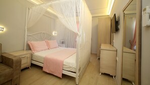 A bedroom with a four-poster bed, a bedside table, a wardrobe, and a mirror. - Ataol Otel (Bozcaada)