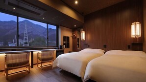 A hotel room with two beds, a seating area with chairs, a large window with a view of mountains, and wooden paneling on the walls. - Seijaku to Magokoro no Yado Nanaeyae (Nikko)