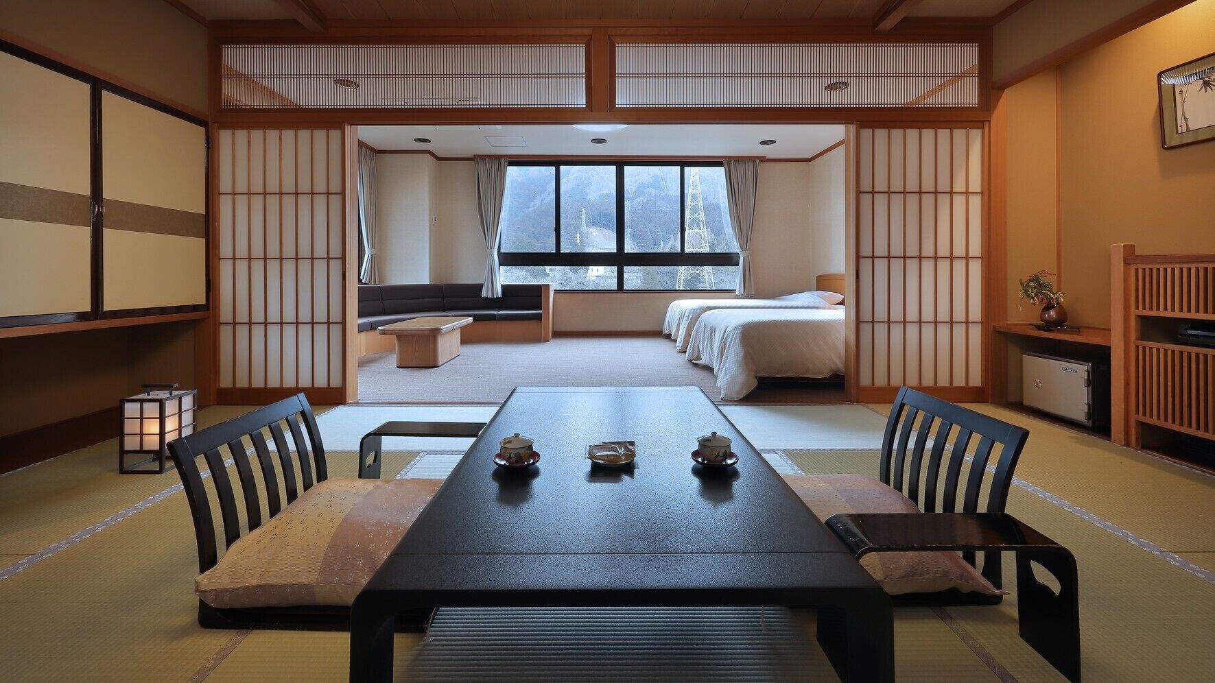 Ein traditioneller japanischer Raum mit Tatami-Böden, einem niedrigen Tisch mit Kissen, einem Futonbett und verschiebbaren Shoji-Schirmen.