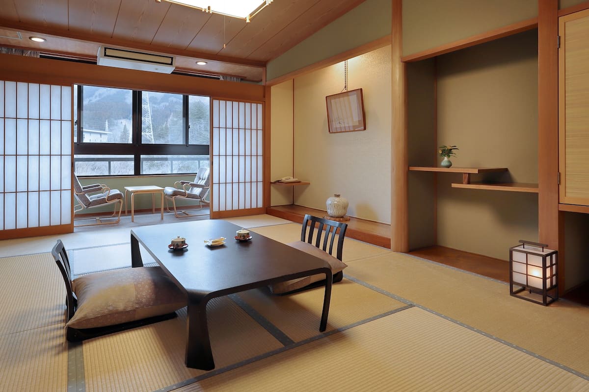 A traditional Japanese room with tatami flooring, a low table with tea sets, and sliding doors.