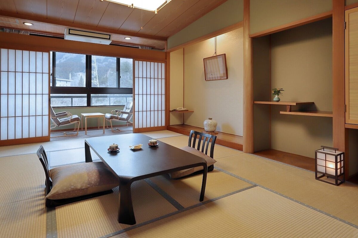 A traditional Japanese room with tatami flooring, a low table with tea sets, and sliding doors.