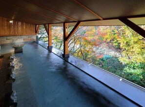 A covered outdoor area with a stone bench, wooden beams, and a view of autumn foliage. - Seijaku to Magokoro no Yado Nanaeyae (Nikko)