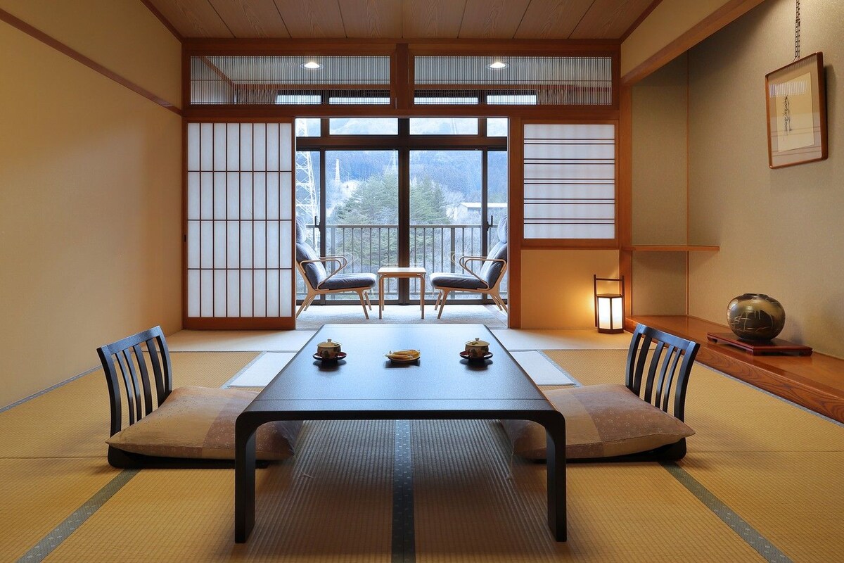 Una habitación tradicional japonesa con suelo de tatami, una mesa baja y puertas correderas shoji.