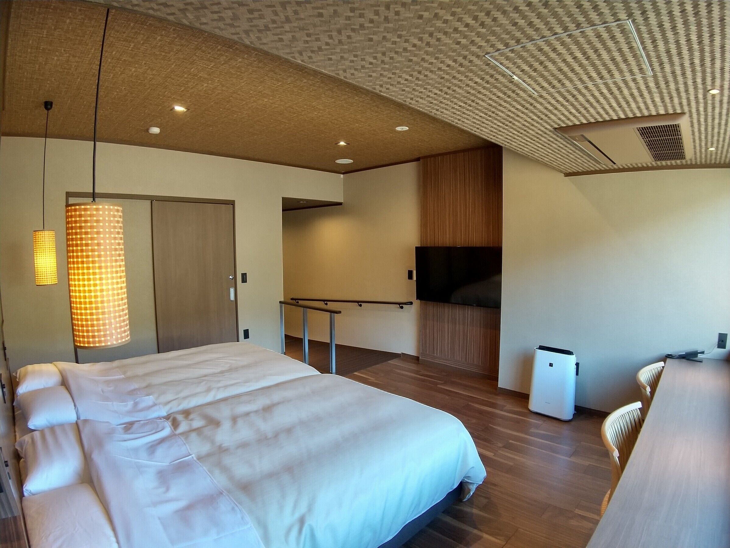 Ein modernes Hotelzimmer mit einem großen Bett, einem Fernseher, einem Schreibtisch und einer Sitzecke.