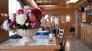 A dining area with a table set for two, featuring a white vase with flowers and a bottle of perfume. - Hotel Michela (Male)