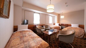 Habitación de hotel con dos camas, un escritorio, un televisor y una mesa de comedor con sillas.