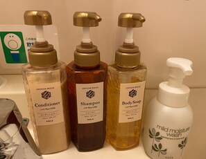 Tres botellas de productos de baño: acondicionador, champú y jabón de cuerpo, cada uno con dispensador de bomba.