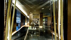 A corridor with a polished floor, bamboo columns, and a central decorative piece.