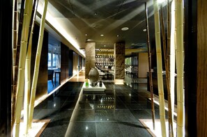 A corridor with a polished floor, bamboo columns, and a central decorative piece.