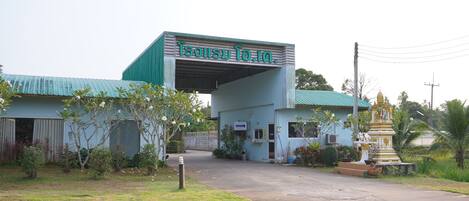 A building with a sign reading "Isusu To. In." and a small shrine-like structure in front.