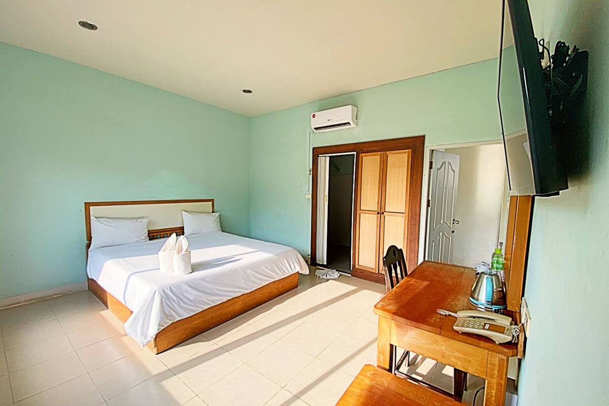 Ein Hotelzimmer mit Bett, Schreibtisch, Stuhl, Fernseher und Klimaanlage.