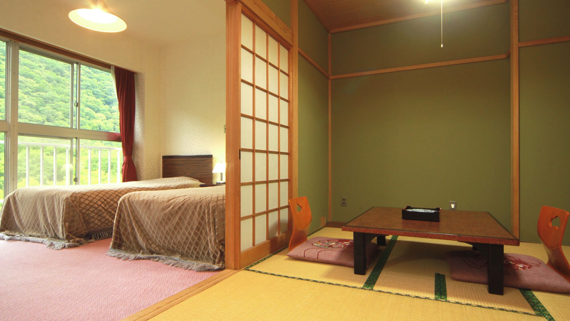 A traditional Japanese-style room with tatami flooring, a low table, and two beds.