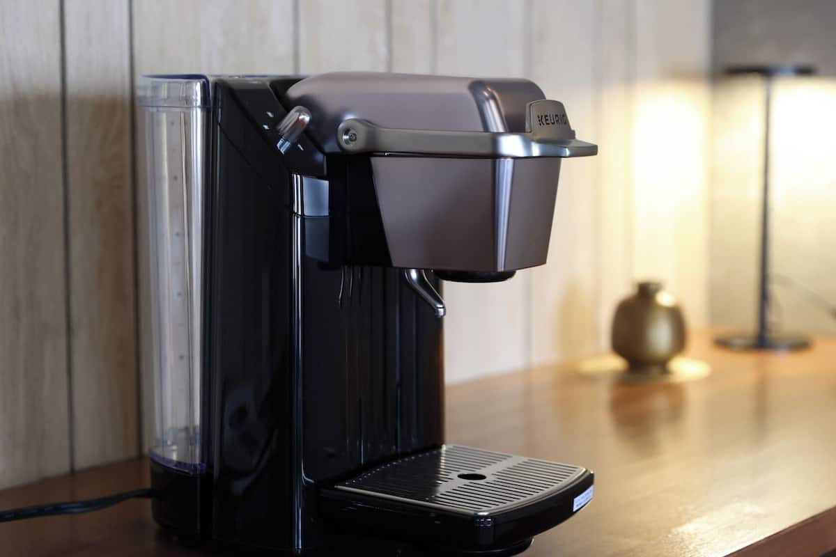 A coffee machine on a wooden countertop with a wall in the background.