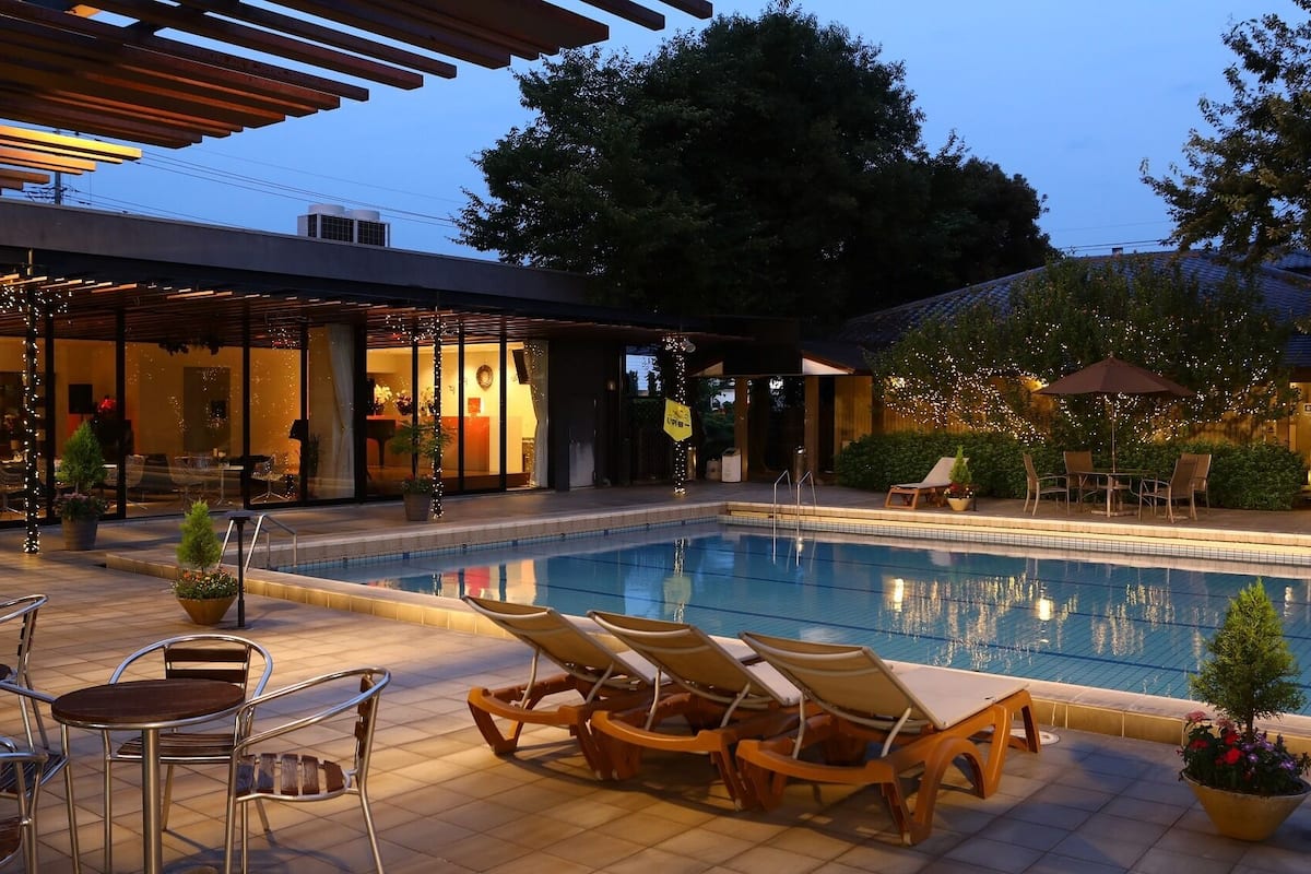 Une piscine avec des chaises longues, un espace salon couvert et un restaurant doté d’une terrasse.