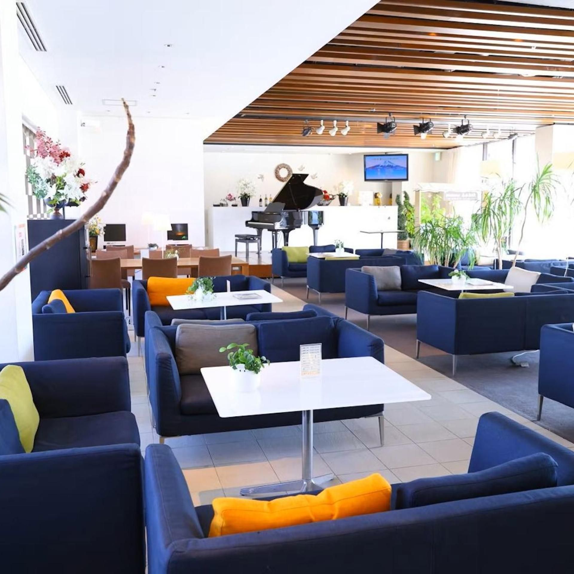 A modern lounge area with sofas, tables, and a piano.