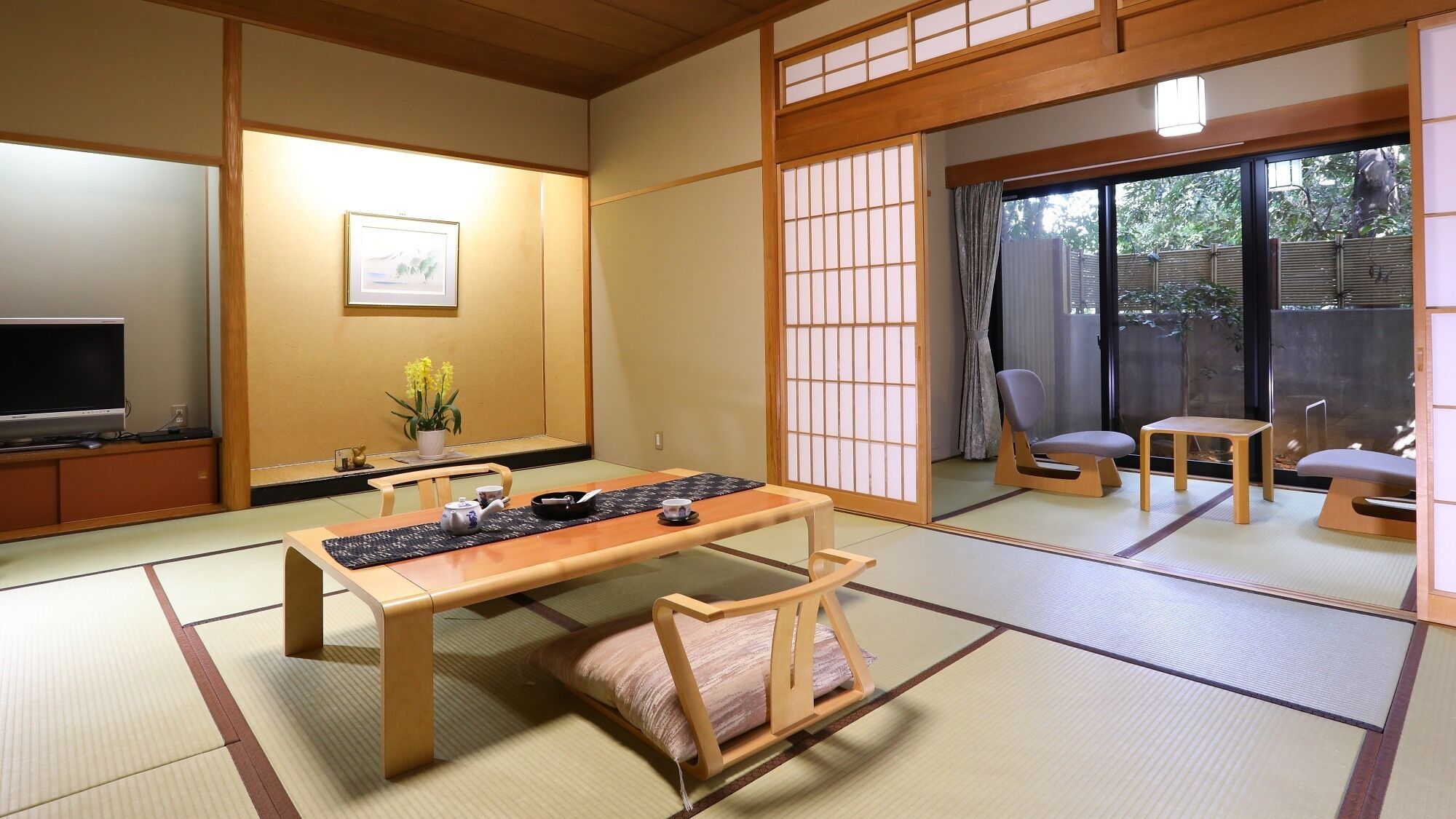 A traditional Japanese room with tatami flooring, a low table, a sofa, and a sliding door leading to a balcony.