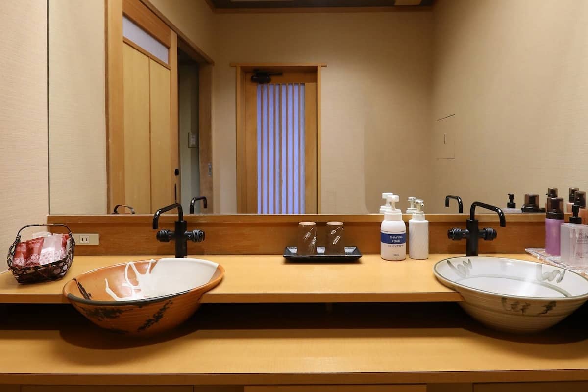 A bathroom with two sinks, a mirror, and toiletries.