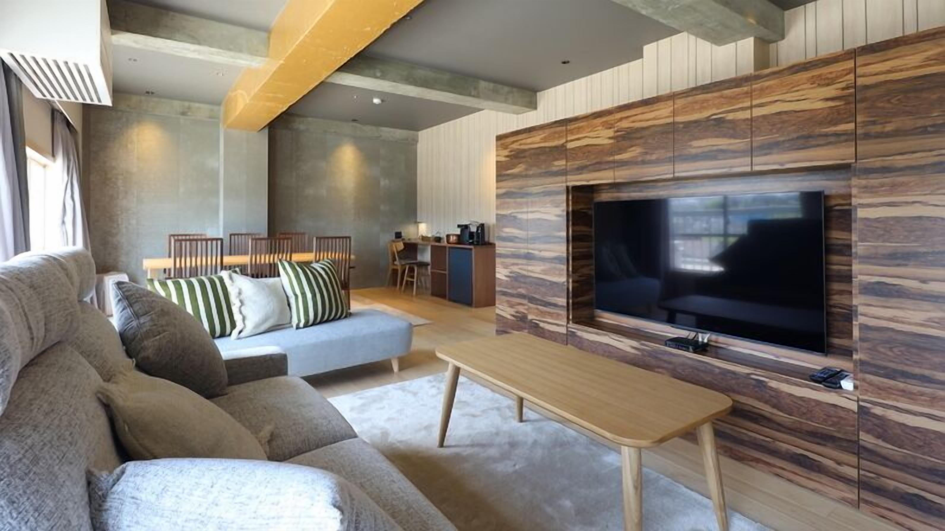 A modern living room with a sofa, TV, and wooden accent wall.