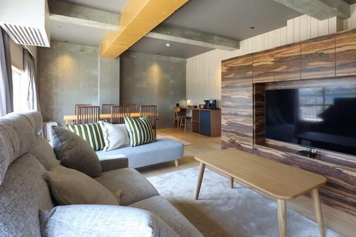 A modern living room with a sofa, TV, and wooden accent wall.