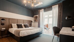 Een moderne slaapkamer met een groot bed, een bureau en een stoel. Er is een raam met gordijnen en uitzicht op de omgeving.