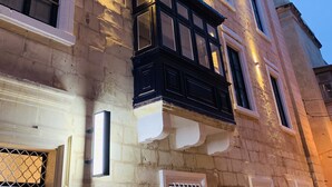 Een meerlaags gebouw met een gevel van steen, grote ramen en een balkon met zwarte relingen.
