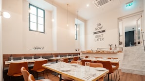 Een restaurantinterieur met meerdere tafels, oranje stoelen en een marmeren vloer.