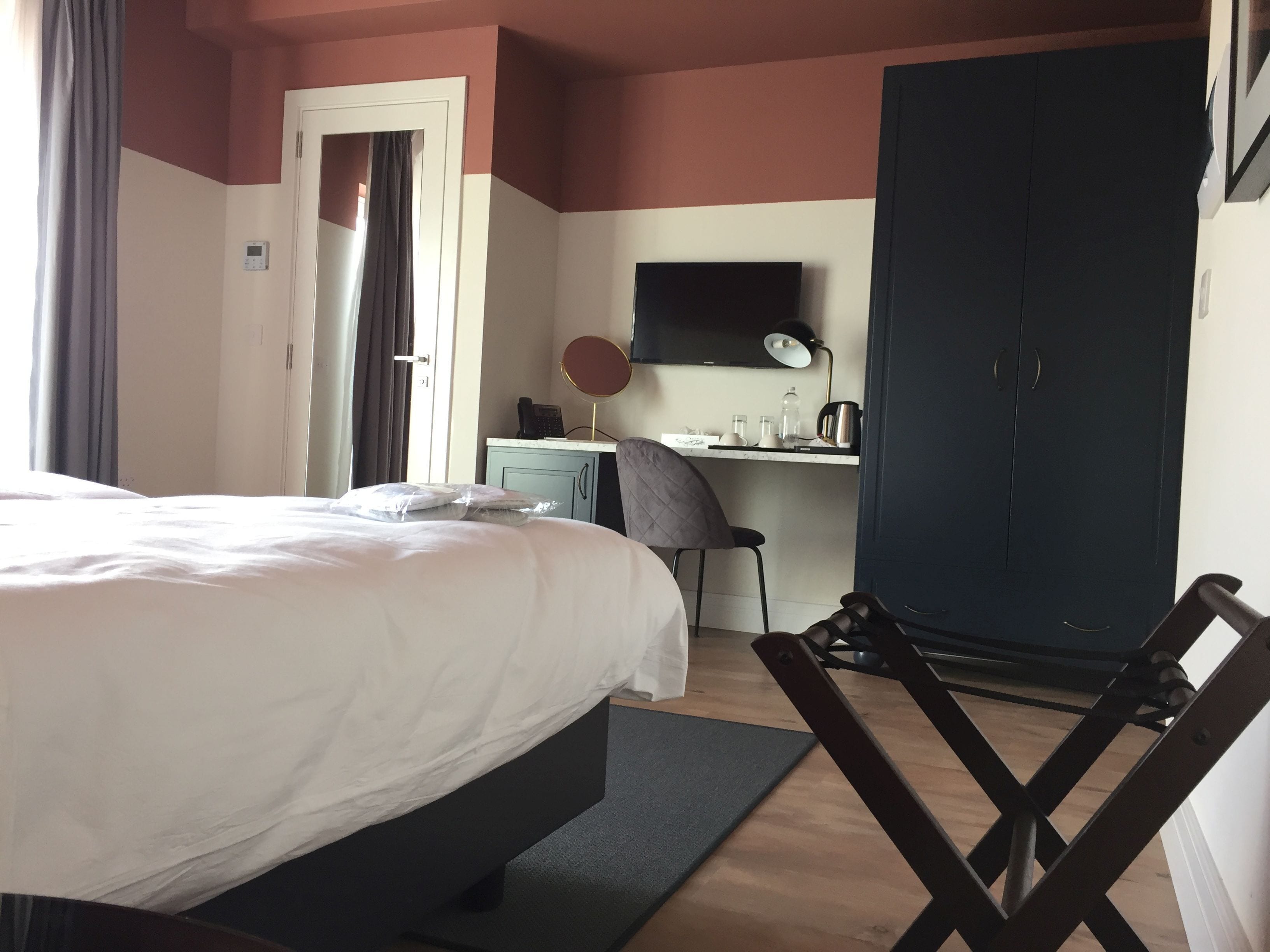Une chambre d’hôtel comprenant un lit, un bureau, une chaise, une armoire et un téléviseur.