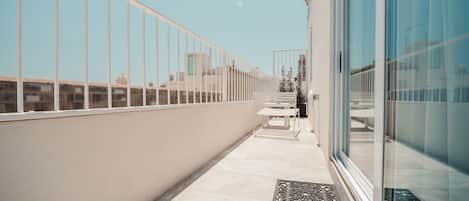 Un balcon avec une balustrade blanche, un banc et une porte donnant sur un bâtiment.