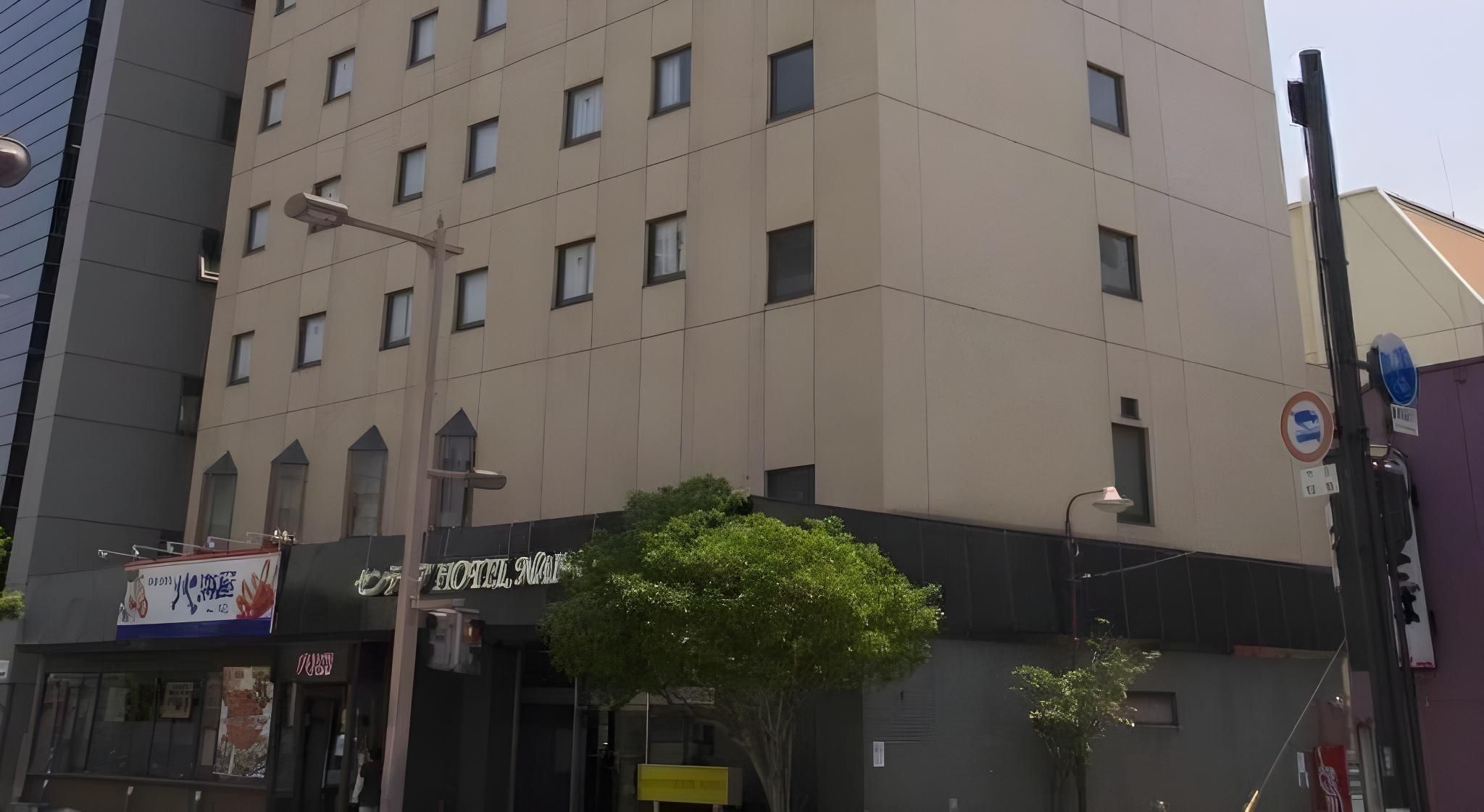 A multi-story hotel with a modern facade, a visible entrance, and a street sign indicating no parking.