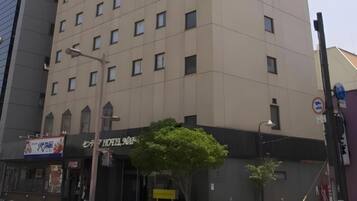A multi-story hotel with a modern facade, a visible entrance, and a street sign indicating no parking.