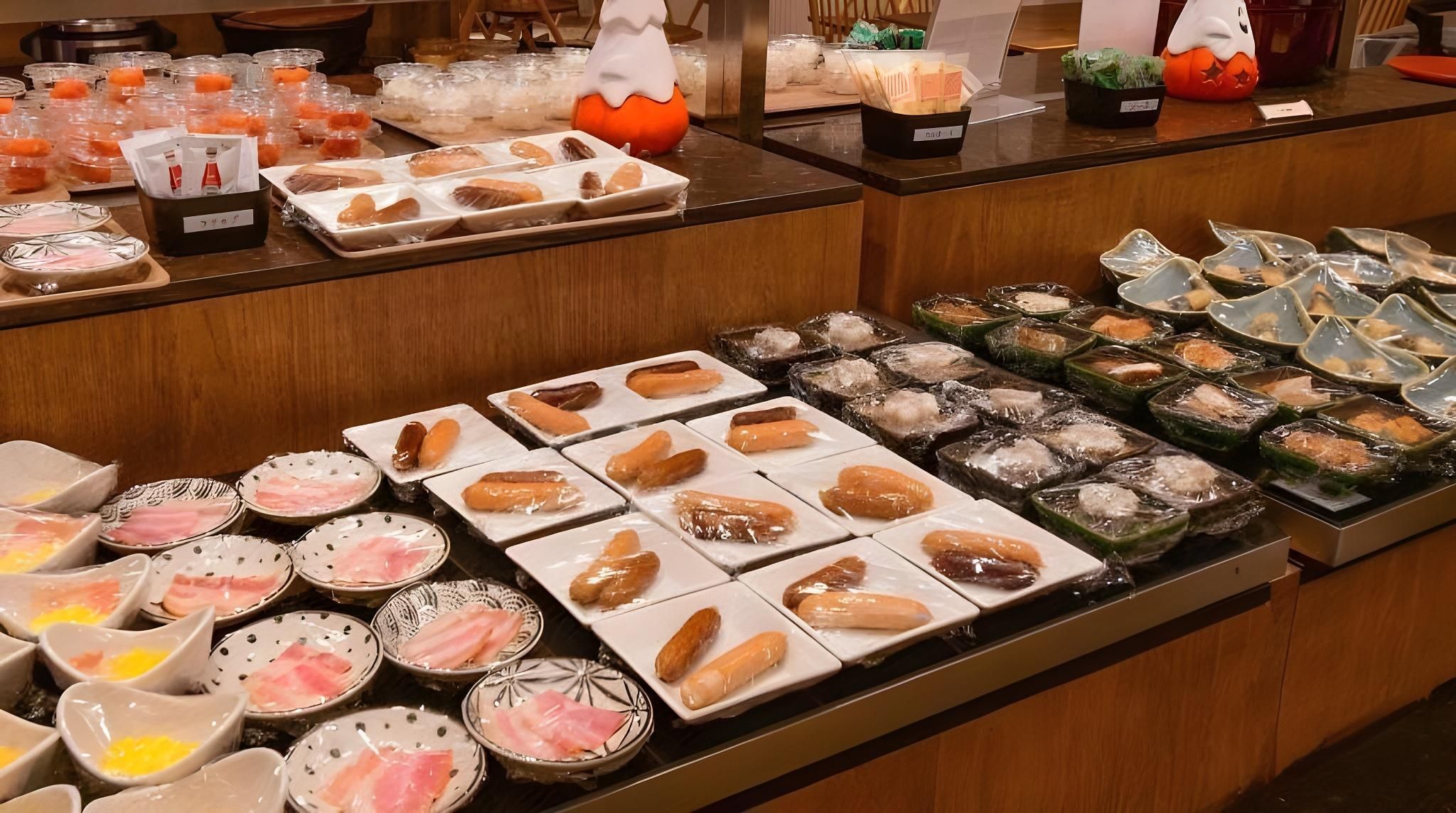 Een buffet met diverse gerechten, waaronder sushi, sashimi en andere specialiteiten.