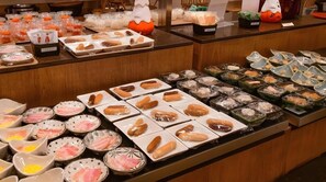 Un bufé con diversos platillos, entre ellos sushi, sashimi y otras opciones.
