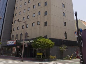 Un hotel con fachada moderna, múltiples ventanas y una entrada visible con señalización.