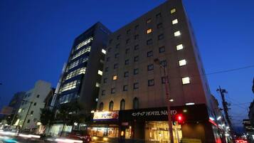 Un edificio de hotel de varios pisos con ventanas iluminadas y un letrero visible que dice 'Hotel Naito'.