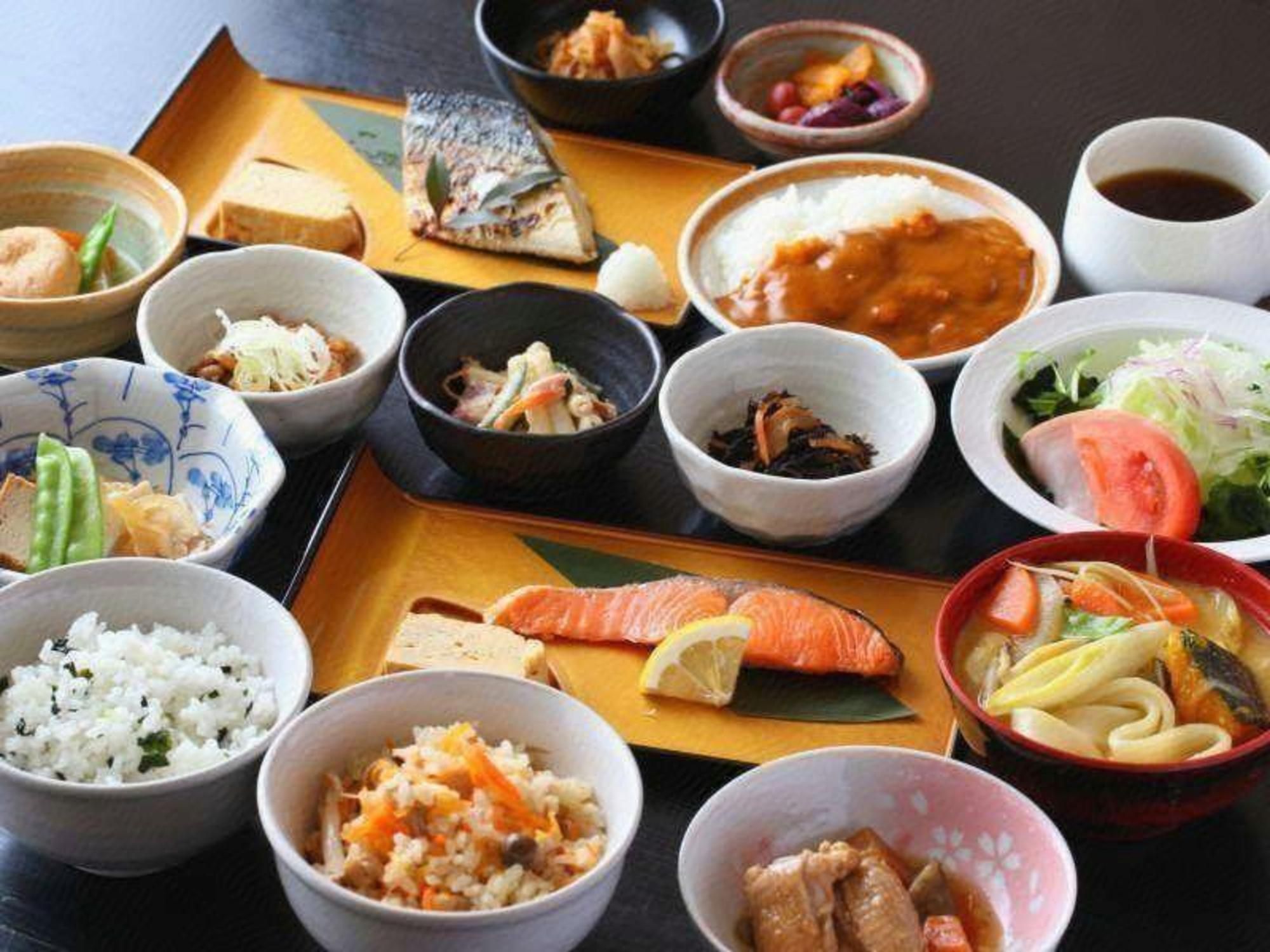 A variety of Japanese dishes arranged on a tray, including rice, fish, and vegetables.
