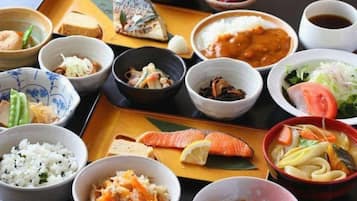 A variety of Japanese dishes arranged on a tray, including rice, fish, and vegetables.