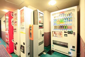 A row of vending machines in a hallway with a patterned carpet.