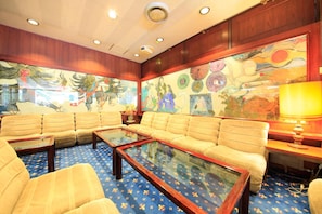 Una habitación con un conjunto de sofás, una mesa de centro de vidrio y un mural grande en la pared.