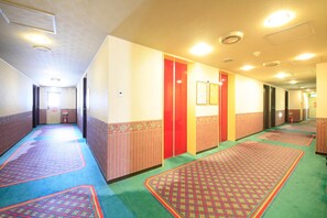 A hotel hallway with carpeted floors, multiple doors, and ceiling lights.