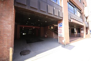 A building entrance with a parking sign, a fire hydrant, and a fire extinguisher.