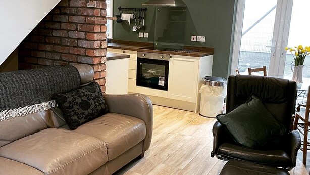 A modern kitchen with a brick wall, a built-in oven, and a window overlooking a bridge. - Pier 36 (Donaghadee)