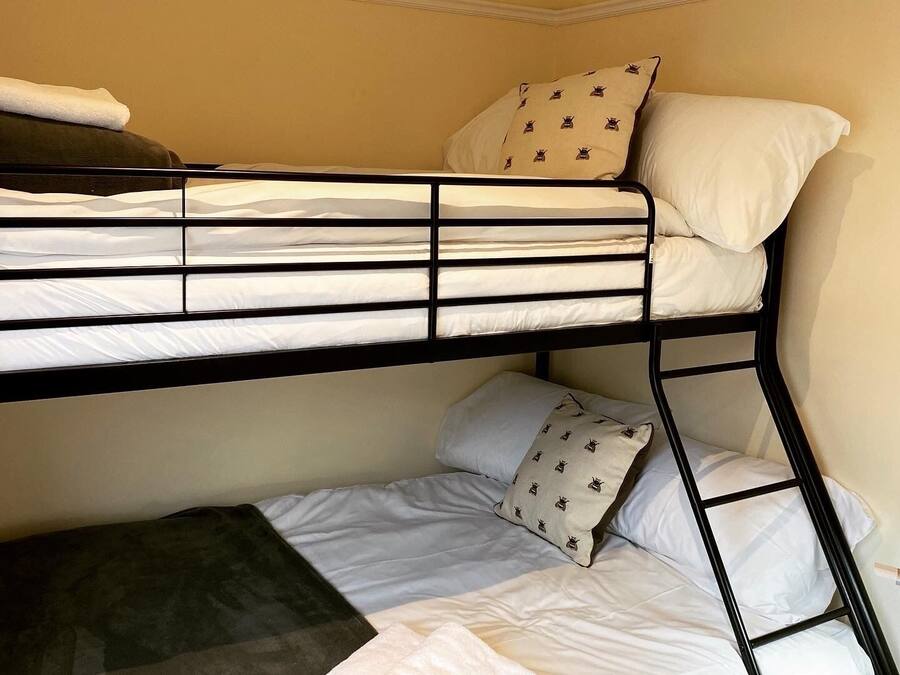 Un letto a castello con biancheria bianca e cuscini fantasia.