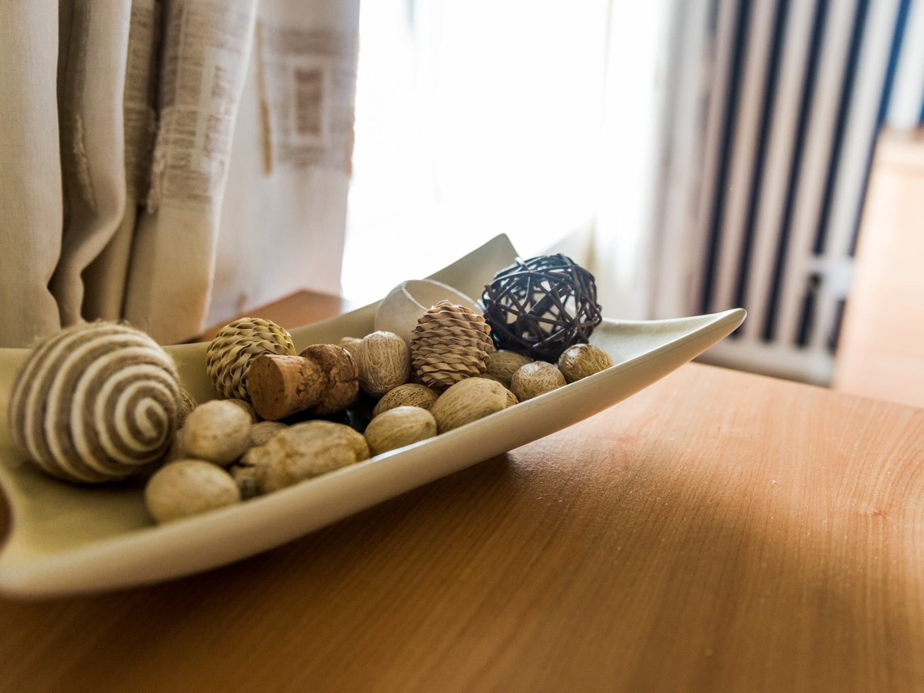 A ceramic plate with various nuts and a decorative ball on a wooden table.