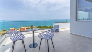 Un balcón con vistas despejadas al mar, dos sillas, una mesa y una planta en maceta.