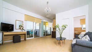 Una sala de estar moderna con sofá, televisor, escritorio y candelabro.