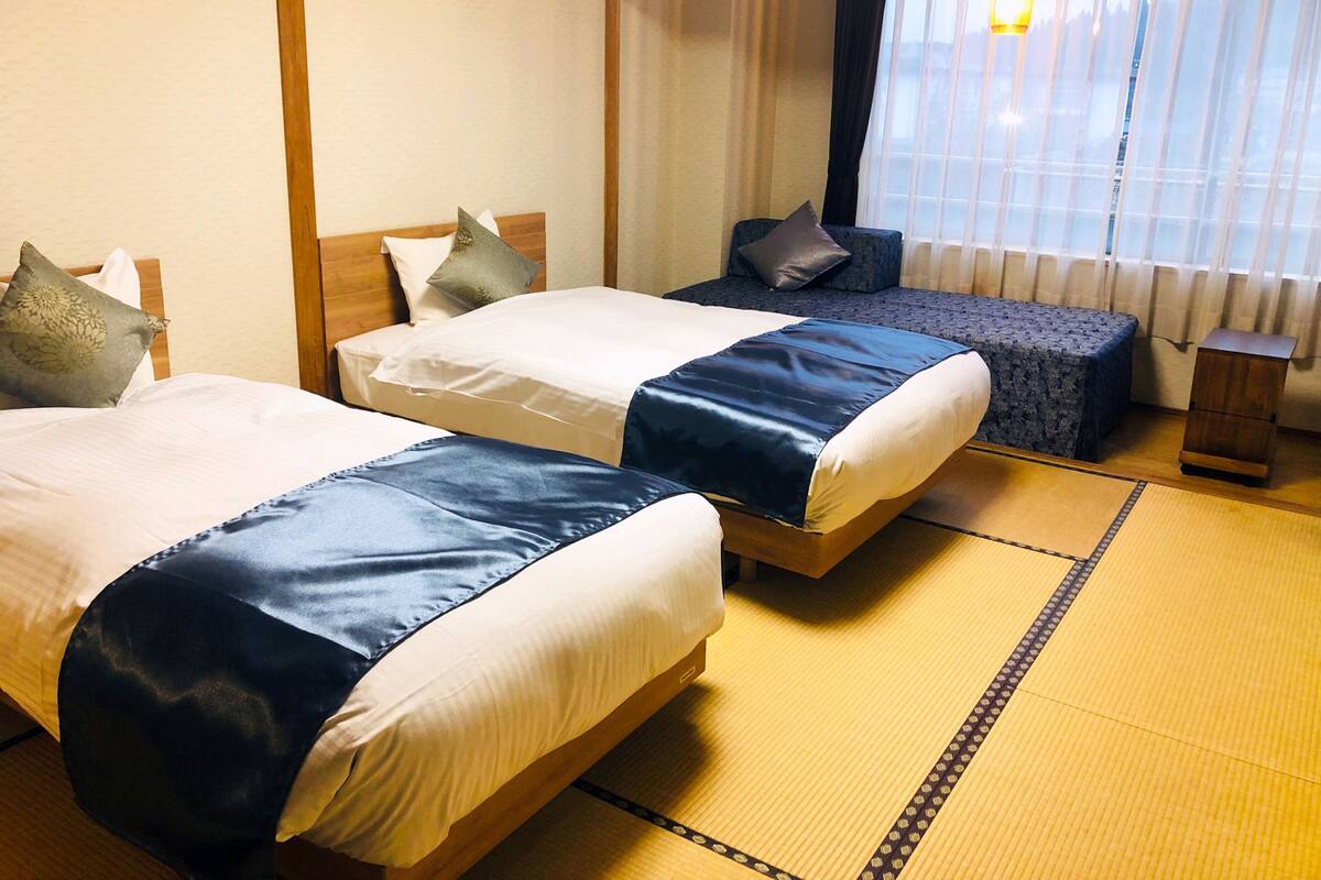 Une chambre d’hôtel avec deux lits, une petite table et une vue sur l’extérieur par une fenêtre.