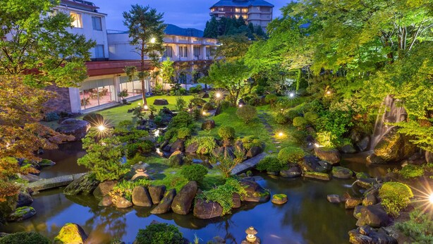 Ein friedlicher Garten mit Teich, Felsen und traditionellen japanischen Laternen.