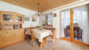 A cozy dining area with wooden furniture, a chandelier, and a view through a glass door.